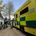 Two clinicians leaving a patient's home and stepping back in to the ambulance.