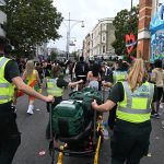 Paramedics at Notting Hill Carnival moving life-saving equipment through crowds.